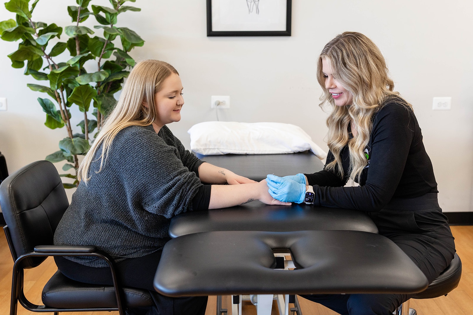 Physical Therapist Dr. Tami treats a patient's shoulder while smiling.