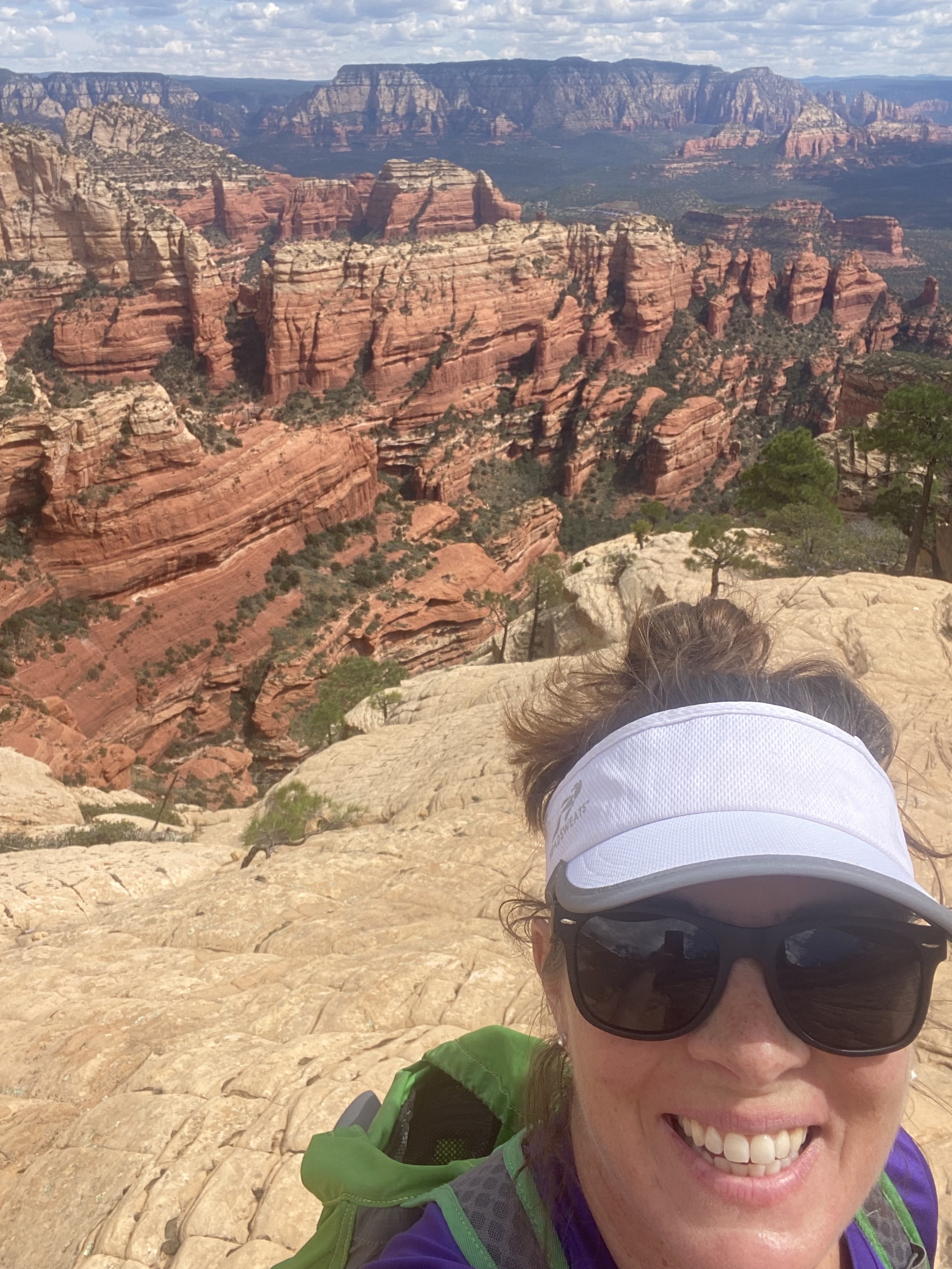 Dr. Carrie Wall smiles in front of a beautiful canyon and rock formation while hiking.